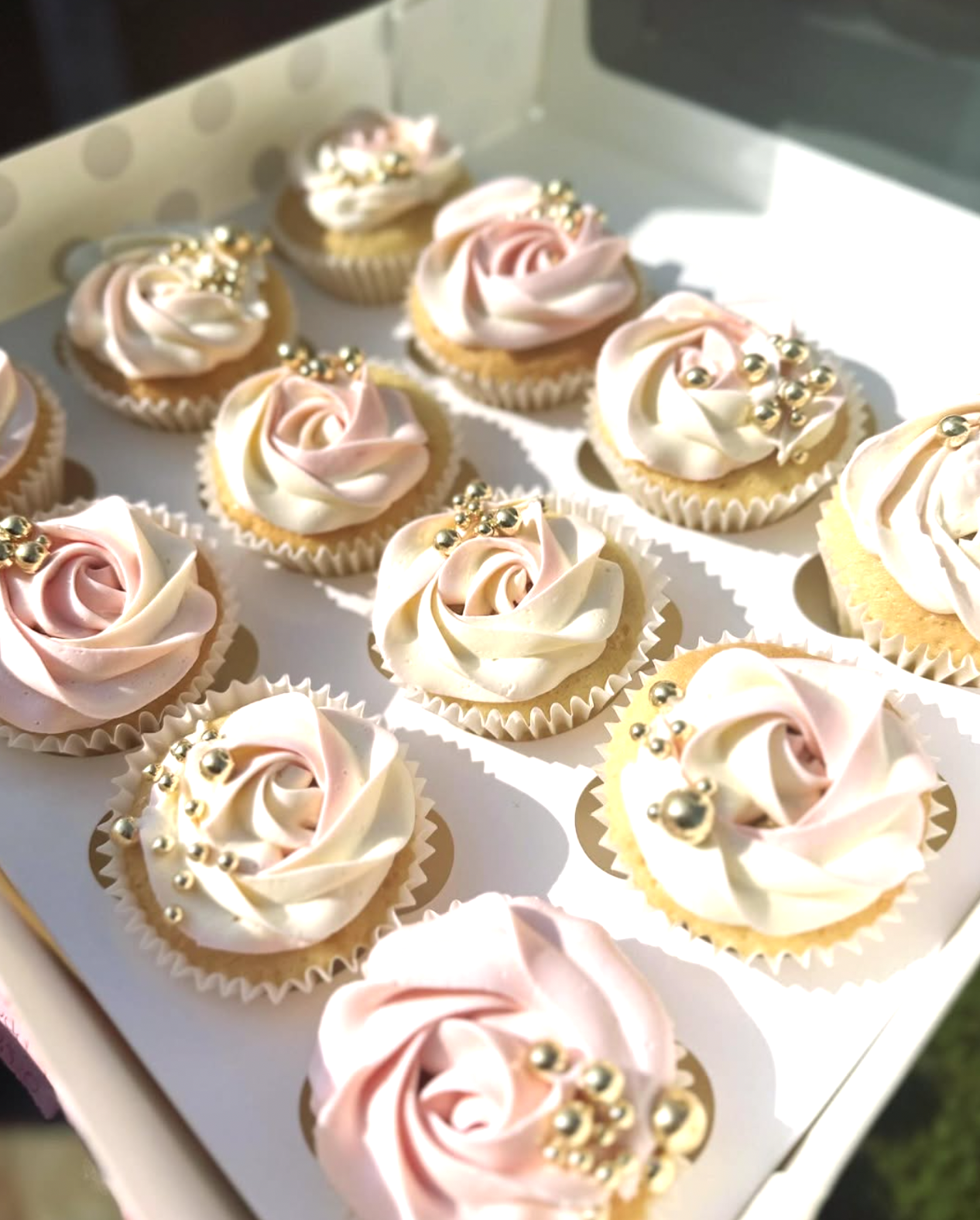 A box of blush and cream rose-piped Cake Plug cupcakes